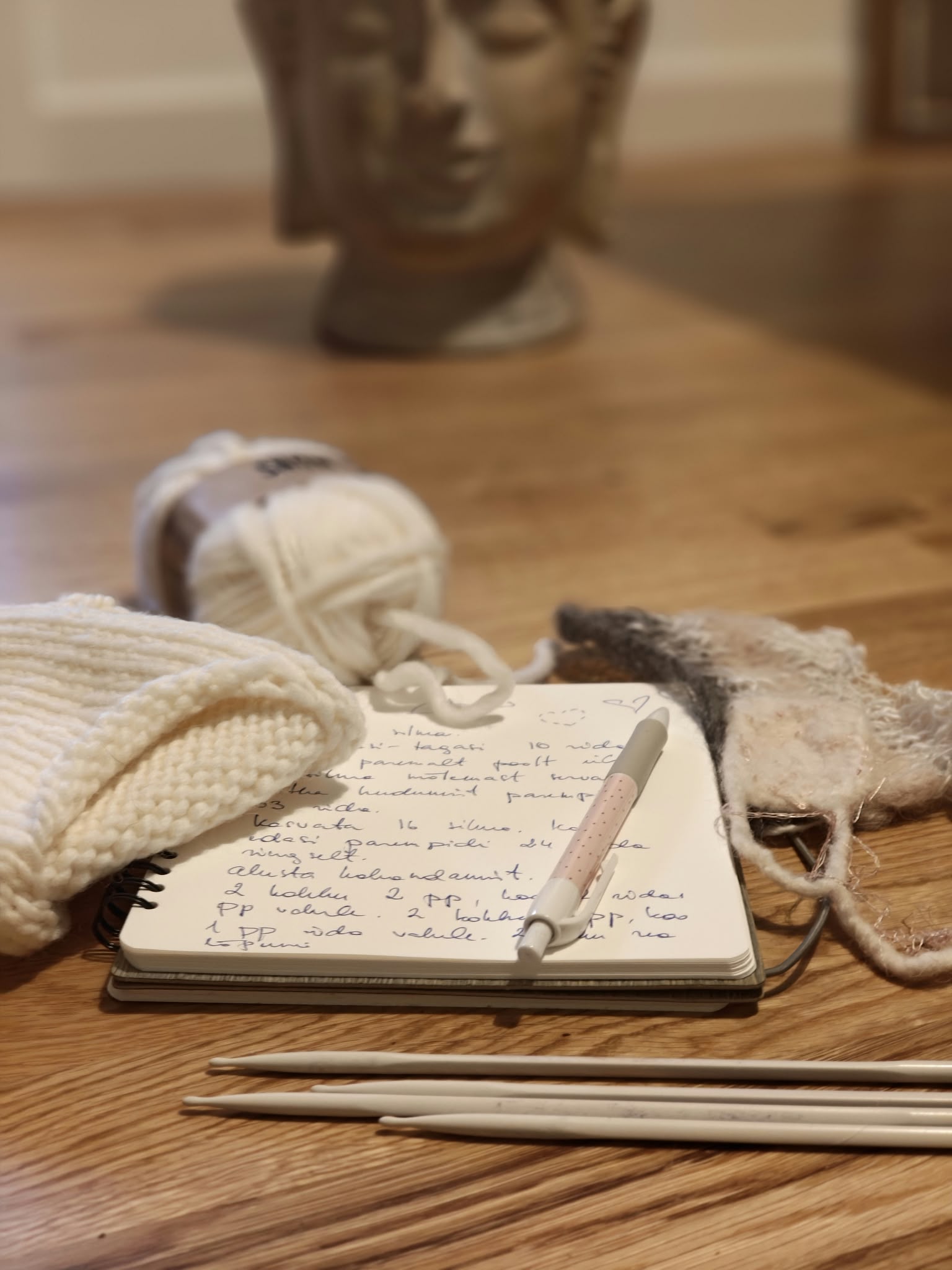Knitting notes, a ball of yarn and felted pieces on a wooden table