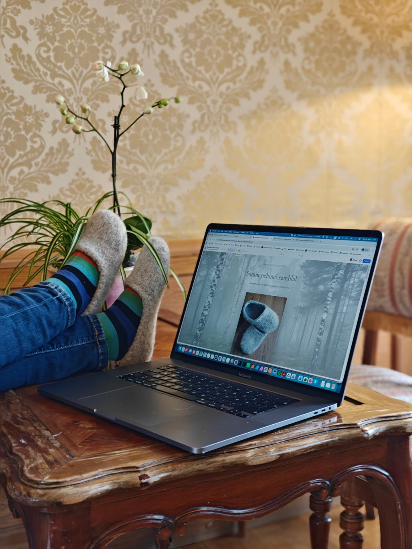 Grey slippers worn beside a laptop